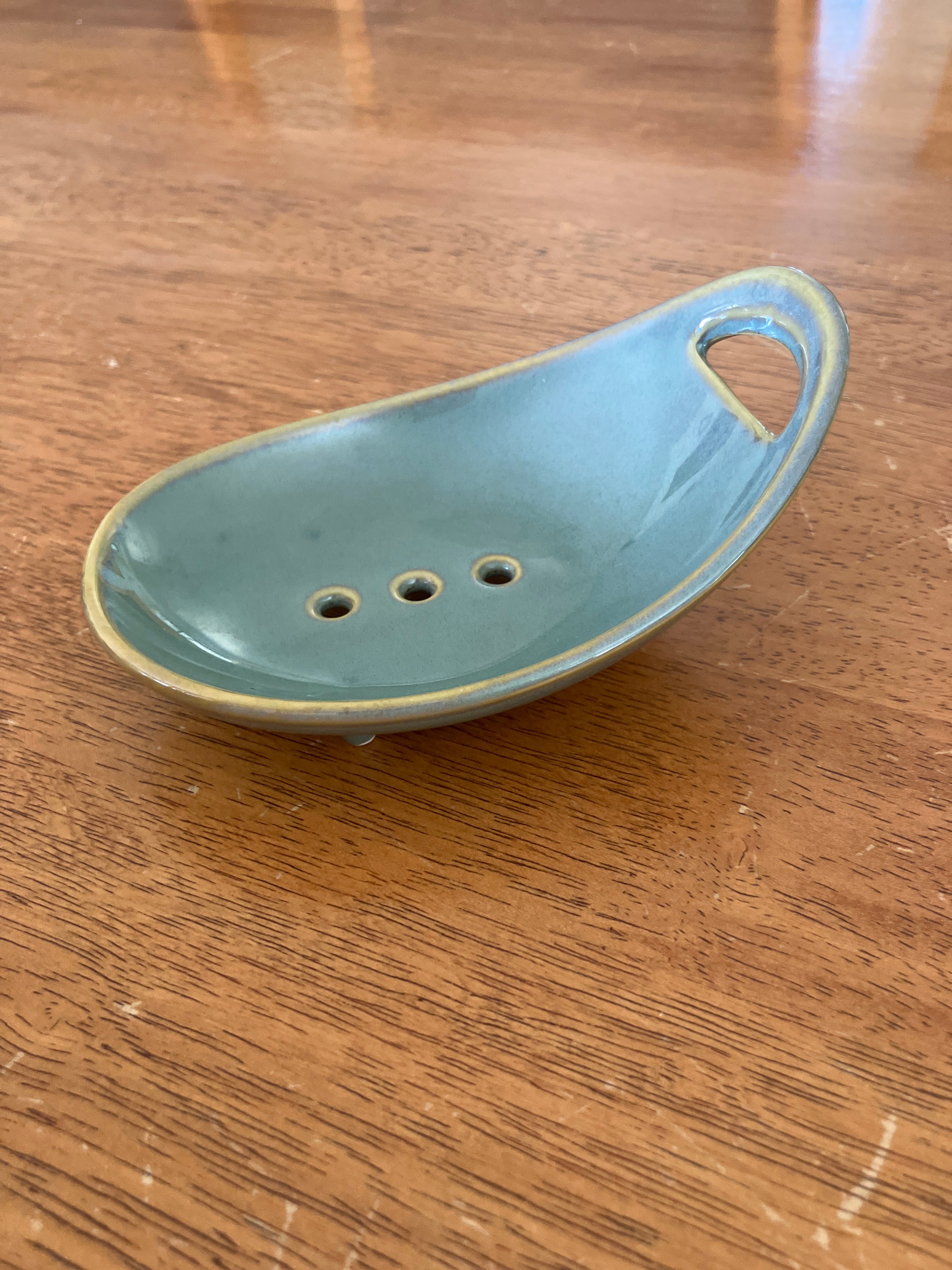 Ceramic soap dish with decorative holes on a wooden surface